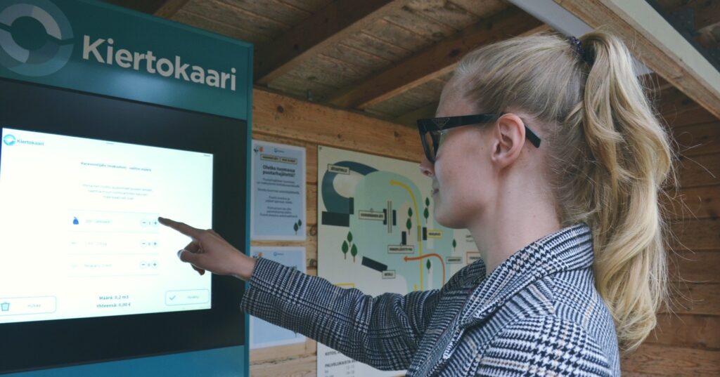 Nainen asioimassa itsepalveluaseman päätteellä.