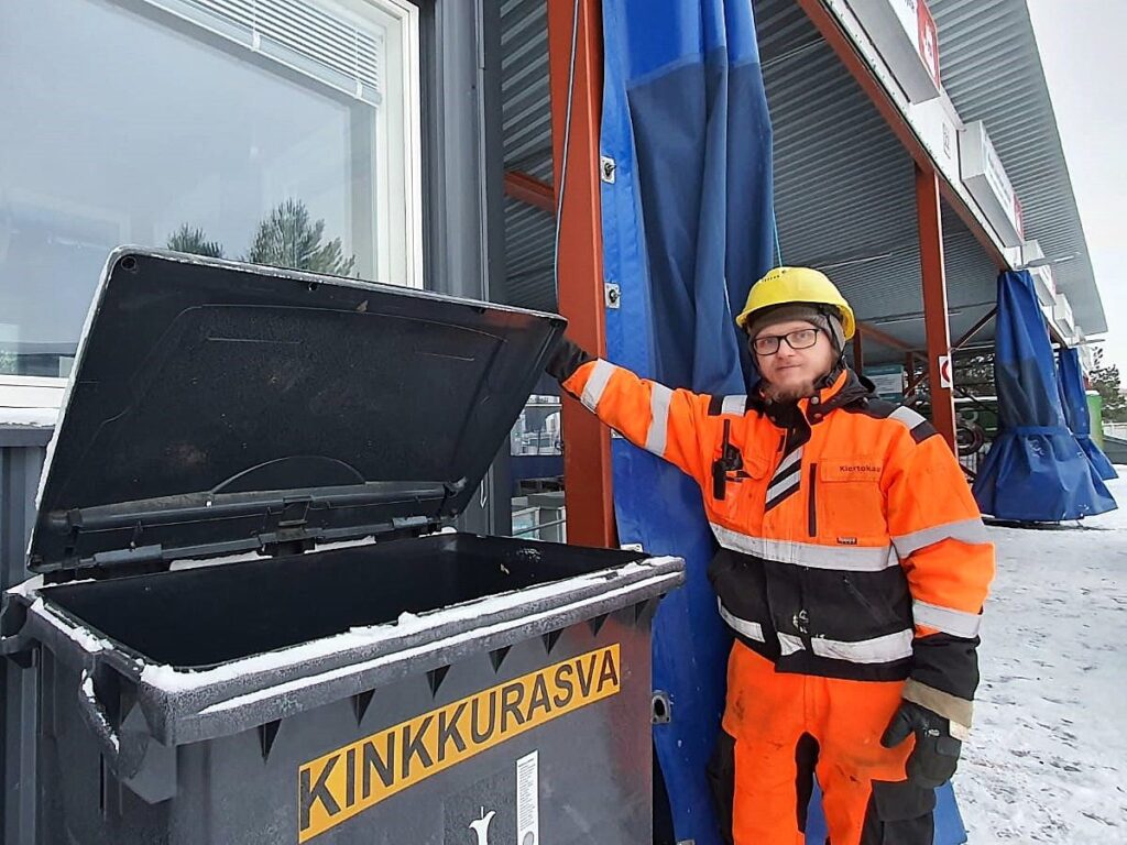 Oivapisteen työntekijä pitää avoinna jäteastiaa, jonka kyljellä lukee kinkkurasva.