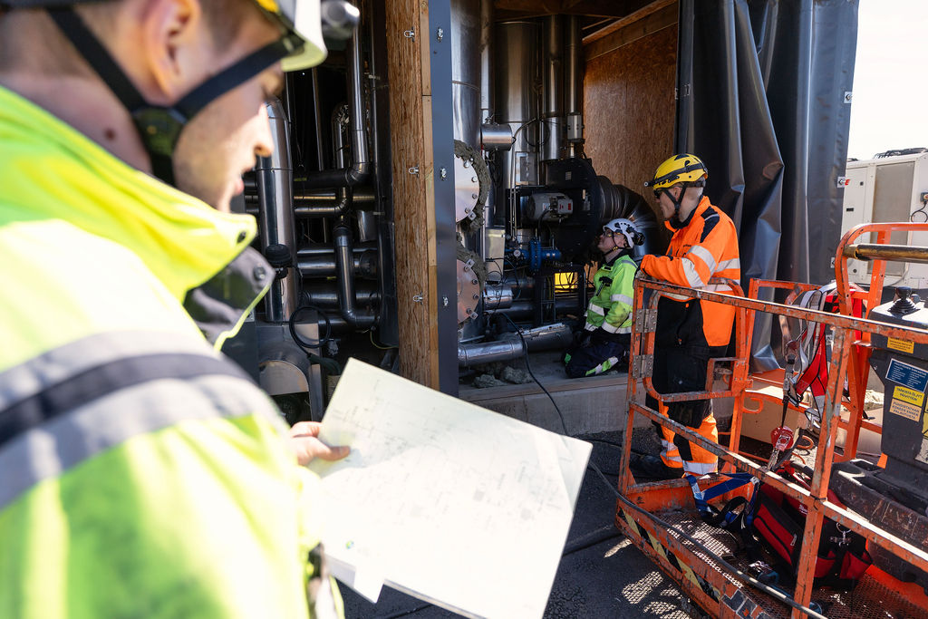 Kolme miestä tutkii biokaasulaitteistoja.