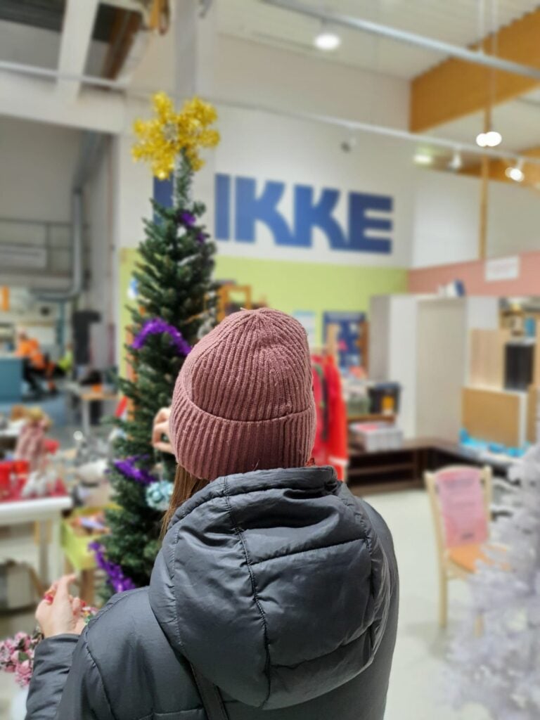Ihminen koristelee tekokuusta kierrätyskeskuksessa.