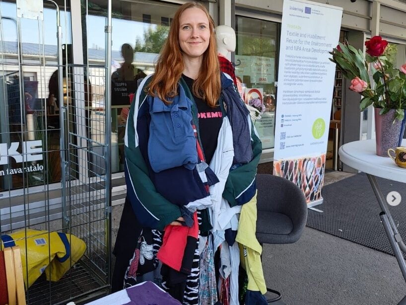 Kiertokaaren työntekijä THREADs-hankkeen pisteellä esittelemässä vaatekuormatakkia, johon oli yhdistetty 38 eri vaatekappaletta.